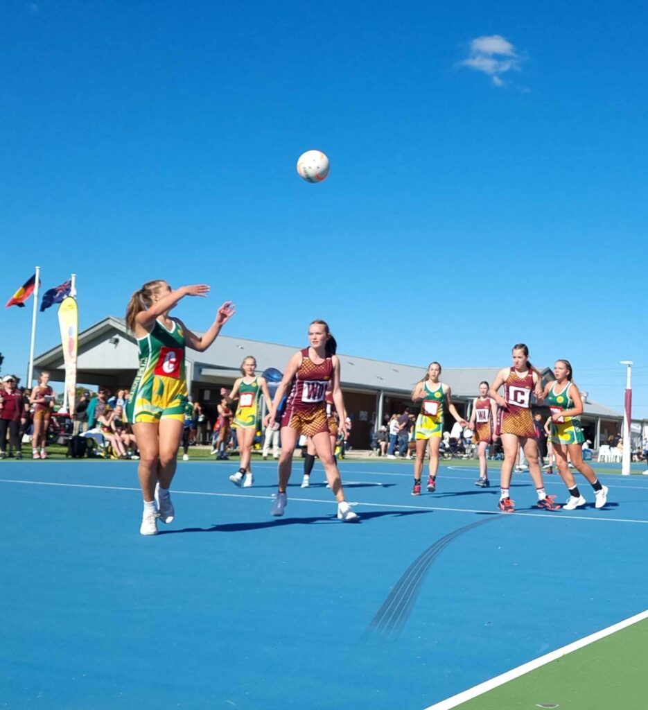 Women actively participating in a netball match on a court, demonstrating skill and collaboration in sports.